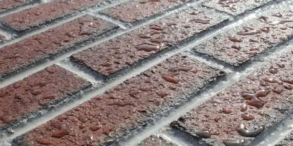 This image shows a close-up view of a brick surface The bricks have a reddish-brown color and appear to be slightly weathered with some cracks and uneven textures visible The bricks are arranged in a diagonal pattern creating a visually interesting and textured surface The image conveys a sense of the rugged durable nature of masonry construction