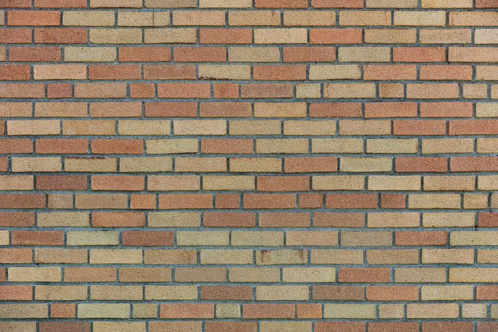 This image shows a brick wall with a repeating pattern of rectangular bricks in various shades of beige tan and brown The bricks are arranged in rows with some variation in the color and texture of the individual bricks The overall appearance of the wall is uniform and structured creating a visually appealing texture